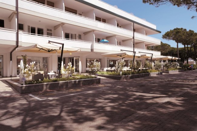 Edificio bianco a tre piani con terrazza e ampi ombrelloni.