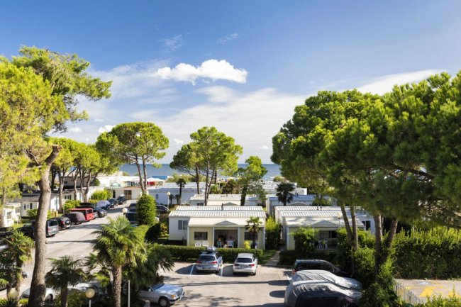 Vista di case tra alberi con il mare sullo sfondo.