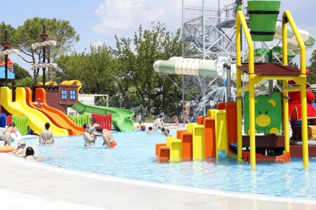 Parco acquatico con giochi d'acqua colorati e scivoli. Persone che si divertono.